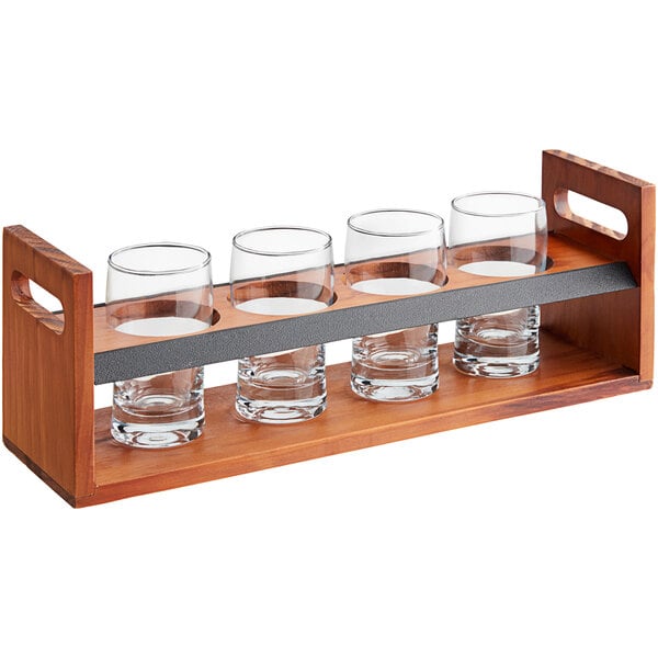 A wooden Acopa tasting flight carrier with four glasses on a wood table.