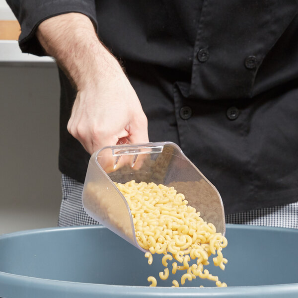 A person using a Rubbermaid Bouncer scoop to put pasta in a container.
