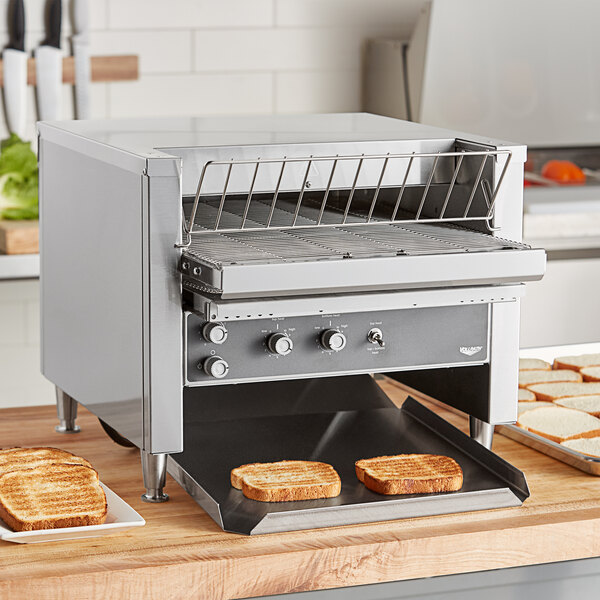 A Vollrath conveyor toaster on a kitchen counter with toast.