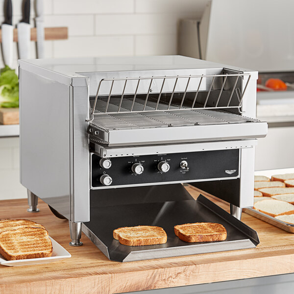 A Vollrath JT2000 conveyor toaster on a counter with toasted bread on a rack.