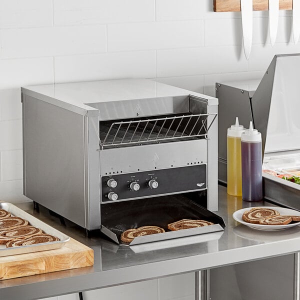 A Vollrath conveyor toaster with cinnamon rolls on the rack.