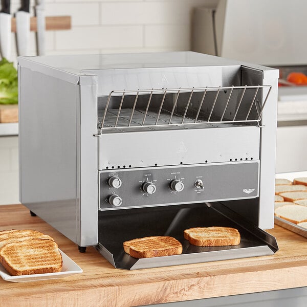 A Vollrath conveyor toaster on a counter with toasted bread inside.