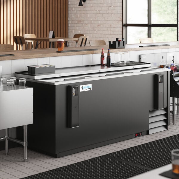 An Avantco black horizontal bottle cooler on a large black counter in a restaurant.