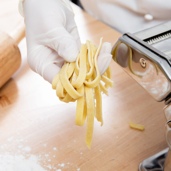 A person using a Weston Roma Manual Pasta Machine to cut pasta.