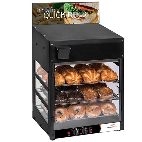 A Nemco humidified countertop display warmer with bagels and muffins inside.