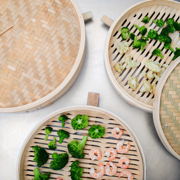 A Town bamboo steamer basket with broccoli and cauliflower inside.