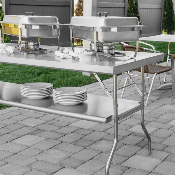 A Regency stainless steel folding work table with food containers on it.