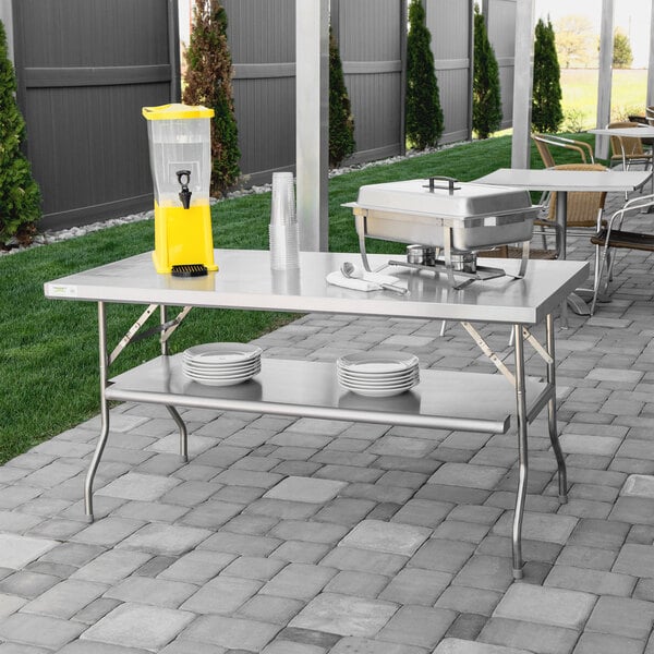 A Regency stainless steel folding work table with plates on it.