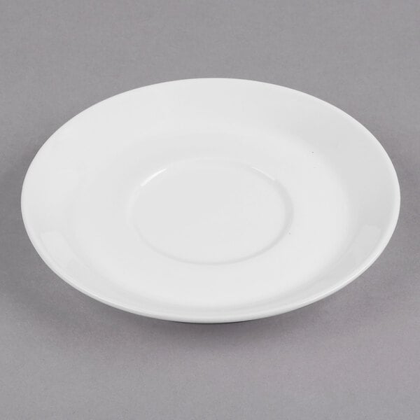 A Libbey Ultra Bright White Porcelain Espresso Saucer with a round edge on a gray surface.