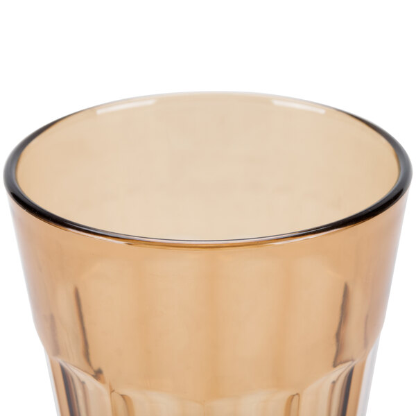 A close up of a Cambro Newport amber plastic tumbler with a rim.