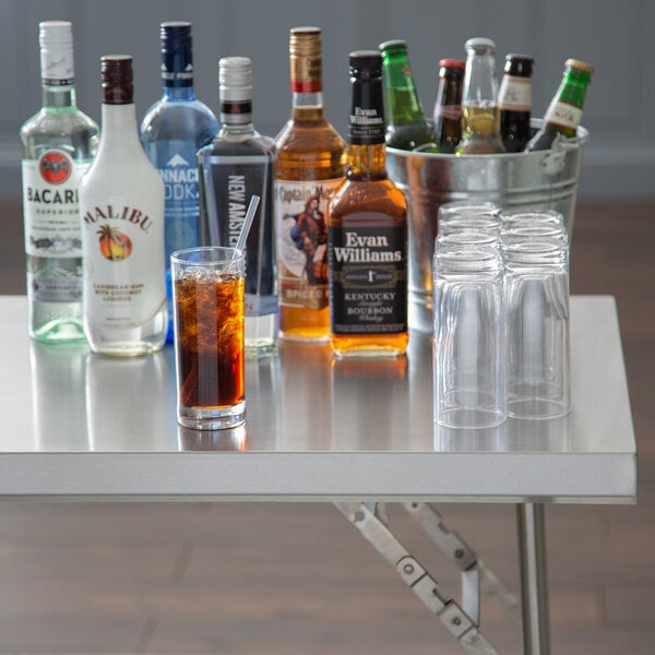 A Regency stainless steel folding work table with a glass of liquid on it.
