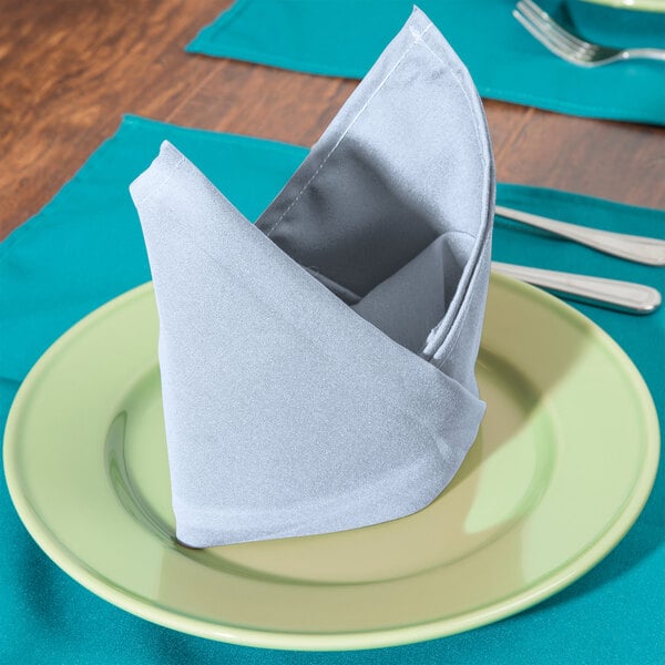 A folded light blue Intedge cloth napkin on a plate.