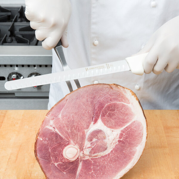 A chef in white gloves using a Dexter-Russell Sani-Safe Narrow Duo-Edge Slicer to cut meat.