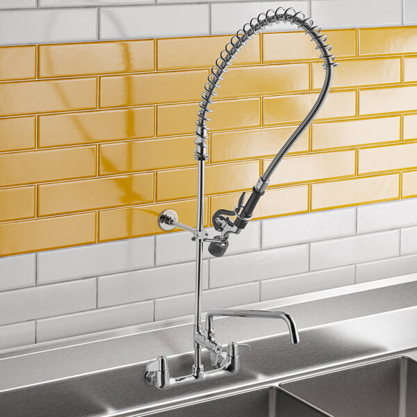 A wall-mounted pre-rinse faucet with an 8-inch center, flexible spray hose, and lever handles, installed above a stainless steel sink.