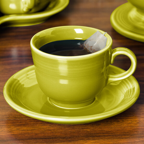 A Fiesta lemongrass saucer with a cup of tea and a tea bag on a table.