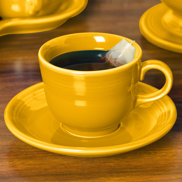 A Fiesta Daffodil saucer with a yellow cup and a tea bag in it.