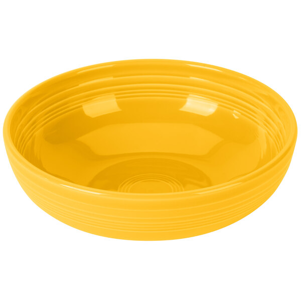 A yellow Fiesta china bistro bowl with a curved surface and lines on the bottom.