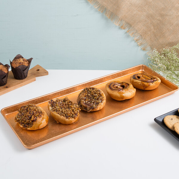 A Chicago Metallic copper bakery display tray with pastries and muffins on it.