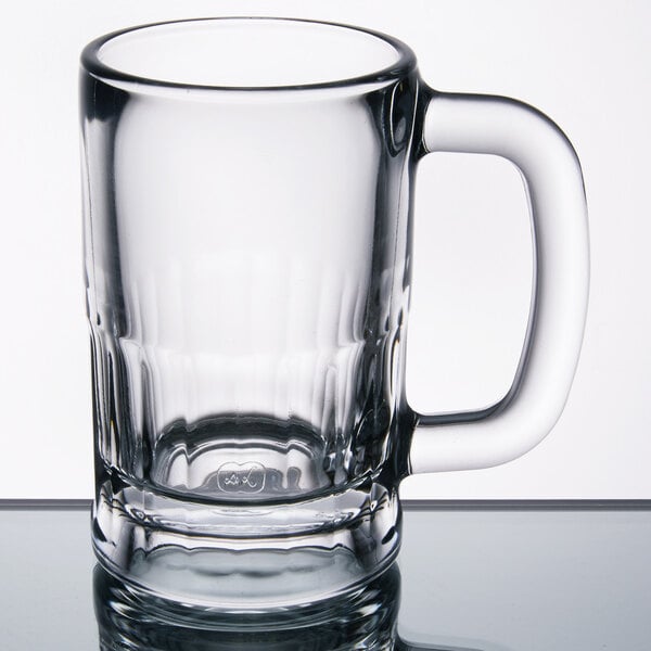 A case of 12 clear Libbey beer mugs with handles on a table.