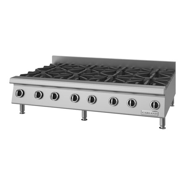 A stainless steel countertop range with eight burners and control knobs.