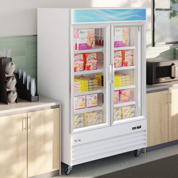 A white glass door merchandiser refrigerator with LED lighting, stocked with frozen food items.
