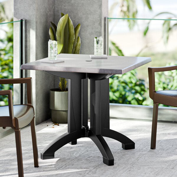 A white outdoor table with two chairs and an umbrella hole.