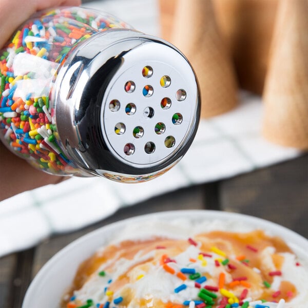 A hand uses a Tablecraft shaker to sprinkle sprinkles on a bowl of food.