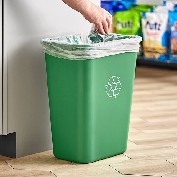 A person putting a can in a green Lavex recycling trash can.