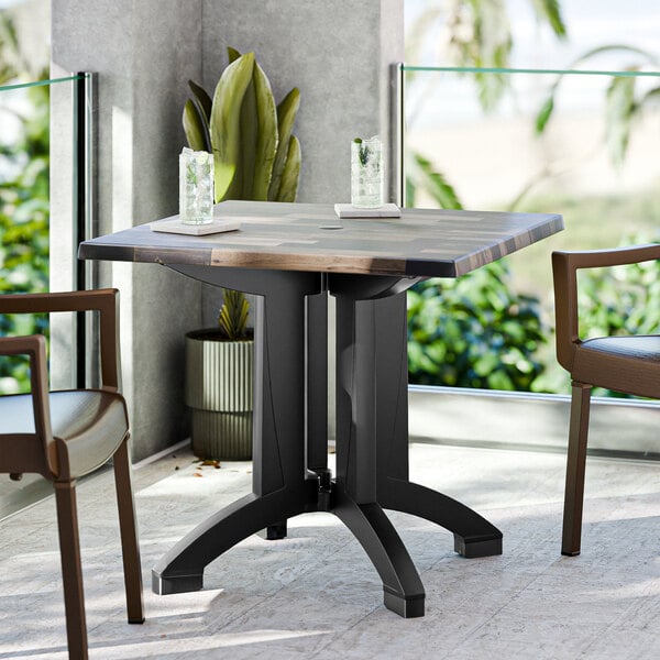 A Grosfillex outdoor table with two chairs on a patio.