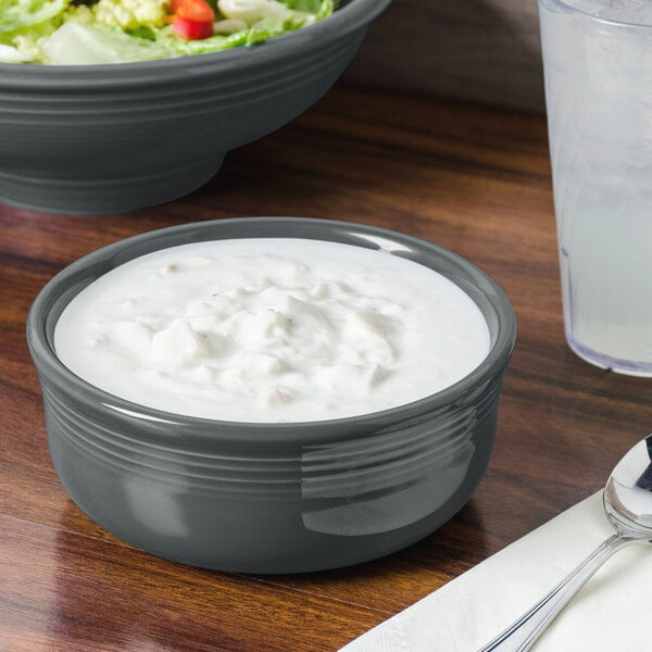 A Slate Fiesta china chowder bowl full of white liquid on a table with a bowl of salad.