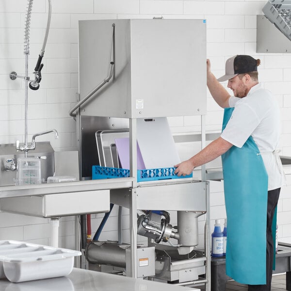 A commercial low temperature door type dishwasher being operated in a kitchen setting.