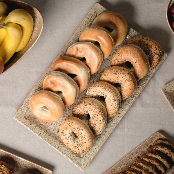 A 10 Strawberry Street rectangular porcelain platter with bagels and bananas on a table in a hotel buffet.