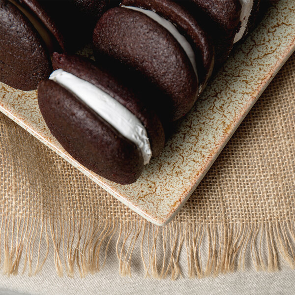 A 10 Strawberry Street Tiger Eye rectangular porcelain platter with chocolate cookies with white frosting.