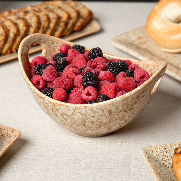 A 10 Strawberry Street Tiger Eye porcelain bowl filled with raspberries and blackberries on a hotel table.