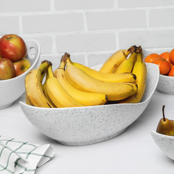 A blue speckled porcelain canoe bowl filled with bananas and apples.