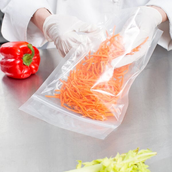 A gloved hand holding a VacPak-It plastic bag of carrots.