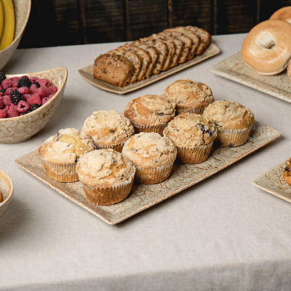 A table with a 10 Strawberry Street Tiger Eye rectangular porcelain platter with food on it, including muffins, bagels, and berries.