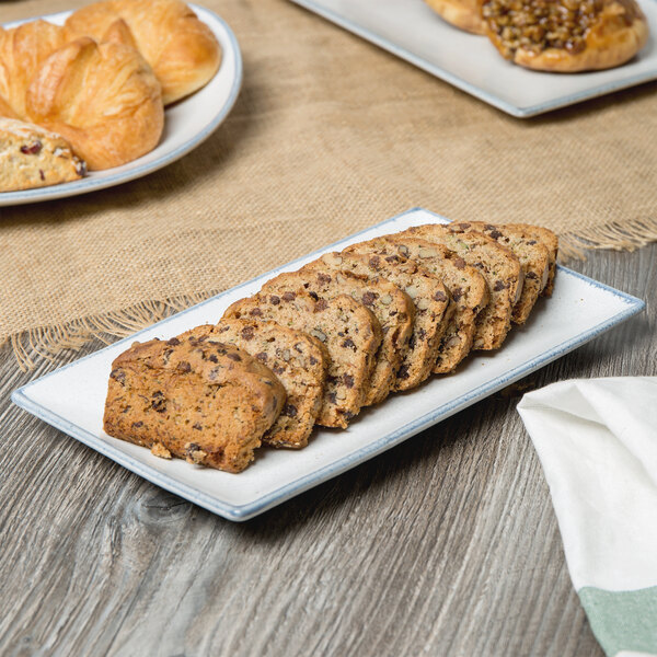 A rectangular porcelain platter with bread and pastries on it.