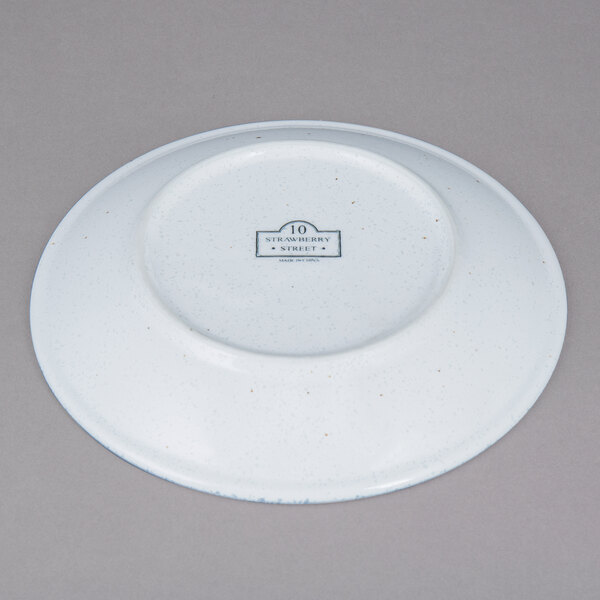 A white 10 Strawberry Street porcelain saucer with a blue speckled design.