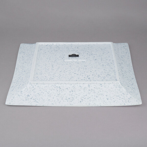 A white square porcelain platter with blue speckles.