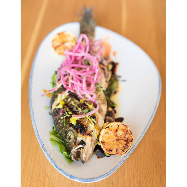 A fish with lemons and onions on a 10 Strawberry Street Arctic Blue porcelain platter.