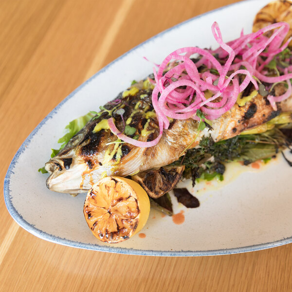 A fish with onions and lemons on a 10 Strawberry Street Arctic Blue platter.