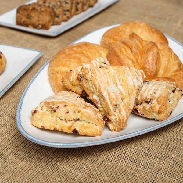 A 10 Strawberry Street Arctic Blue porcelain platter with a variety of pastries on a table.