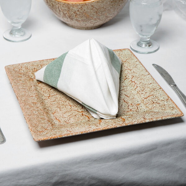 A 10 Strawberry Street Tiger Eye porcelain charger plate with a folded napkin on it.