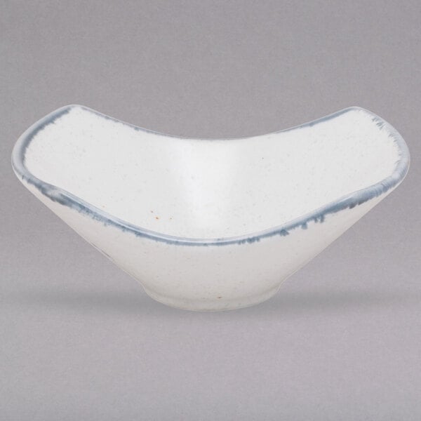 A white porcelain bowl with blue rim and blue and white designs.