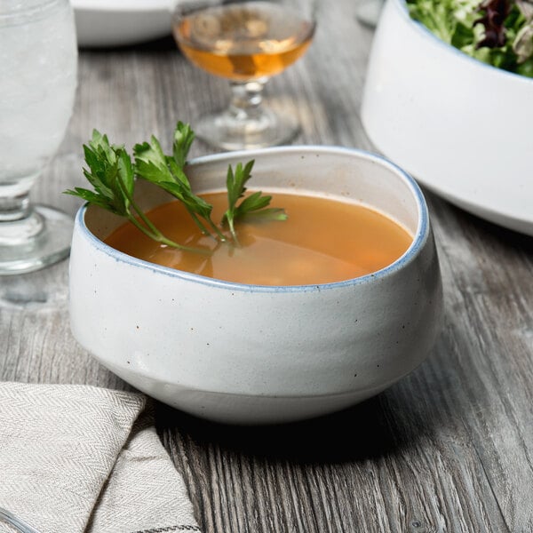 A 10 Strawberry Street Arctic Blue porcelain cereal bowl filled with soup and garnished with parsley.