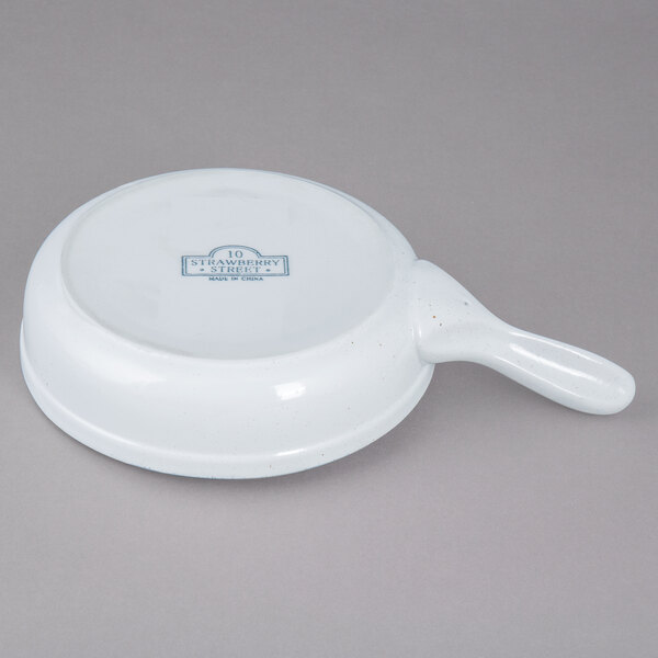 A white porcelain bowl with a handle.