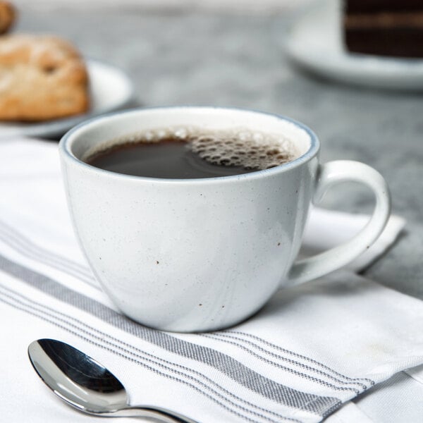 A 10 Strawberry Street Arctic Blue porcelain cup of coffee with a spoon on a napkin.