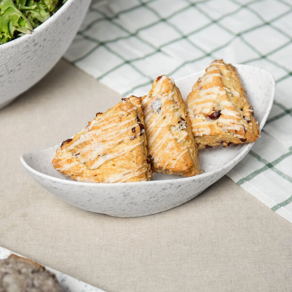 A blue speckled porcelain canoe bowl filled with pastries.