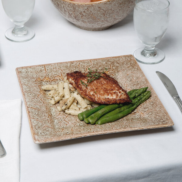 A 10 Strawberry Street Tiger Eye porcelain dinner plate with asparagus and chicken on it.